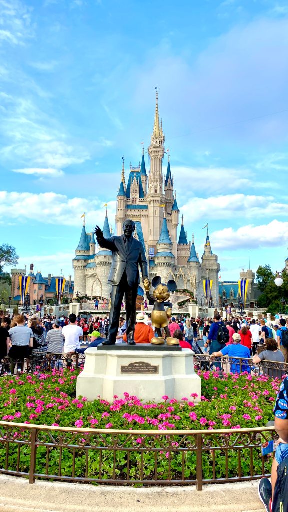 Disney World Cinderella'scastle with a statute of Walt Disney and mickey mouse holding hands in front of the castle